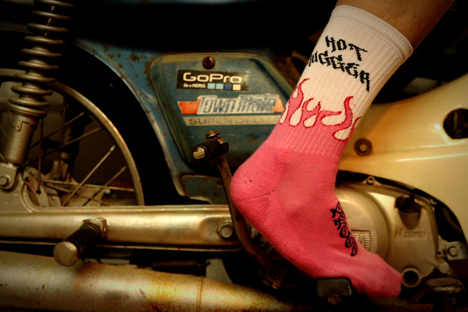 Person wearing a pink sock with text on a motorcycle