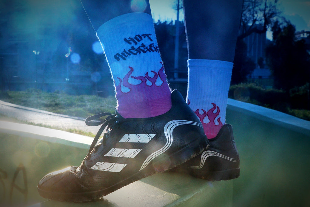 Person wearing black Adidas shoes with colorful socks on a blurred outdoor background