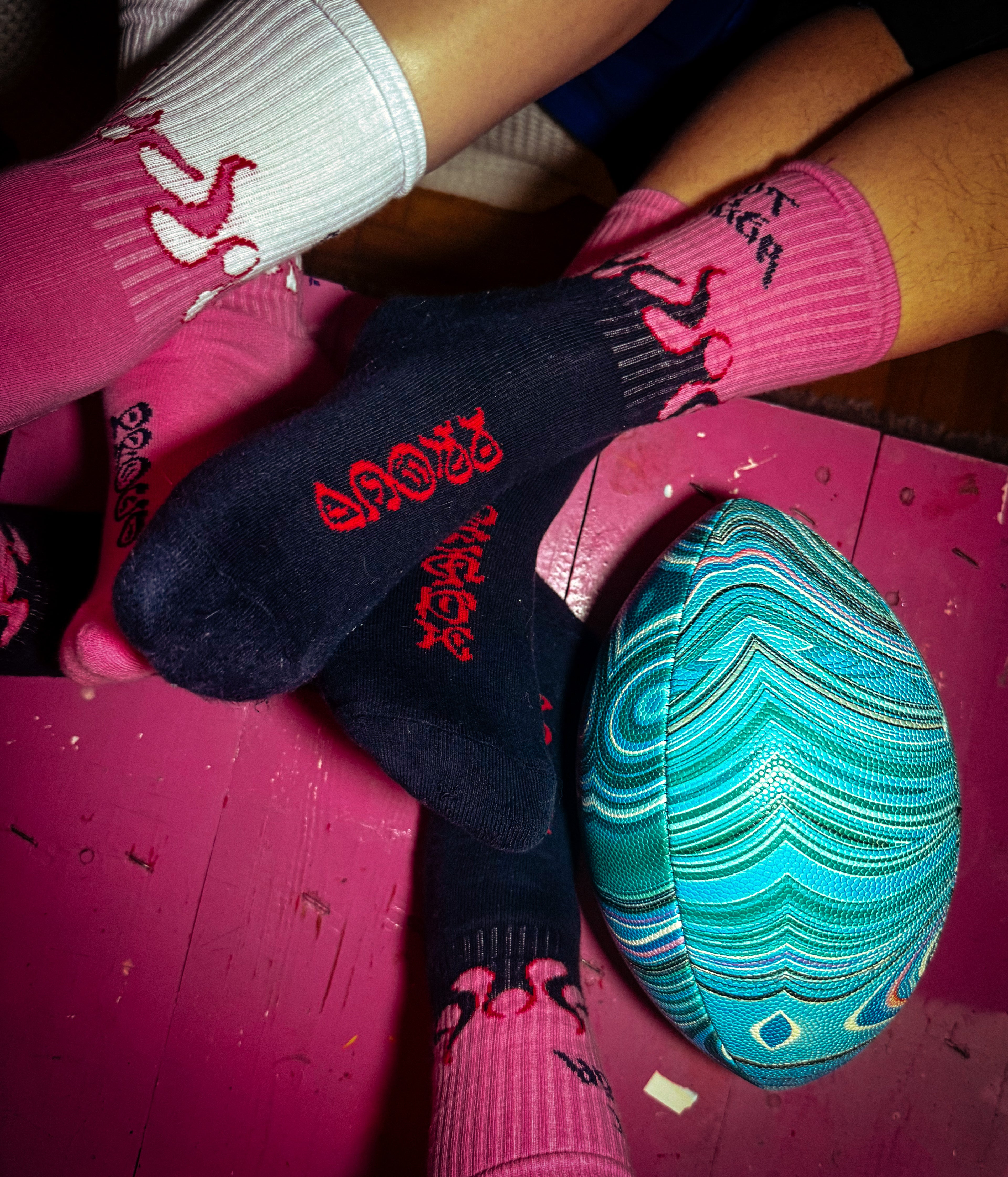 Person wearing pink and black socks with a colorful ball on a pink surface