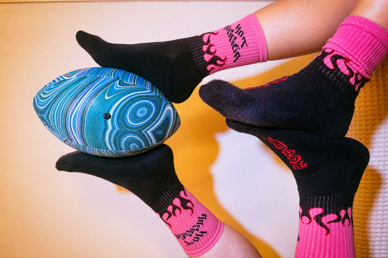 Person wearing black and pink socks with a blue and green object on a blurred background
