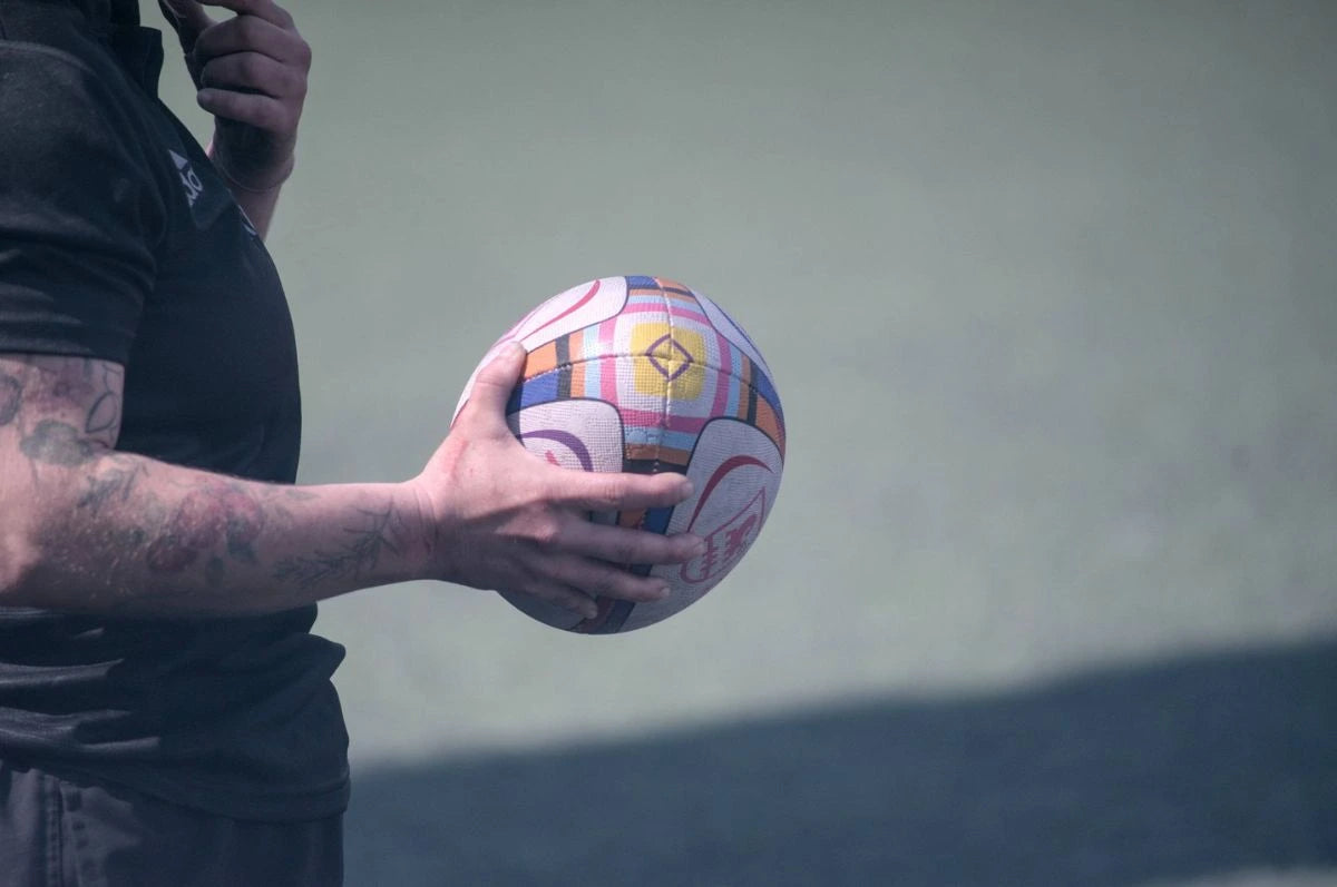 Person holding a colorful soccer ball against a plain background