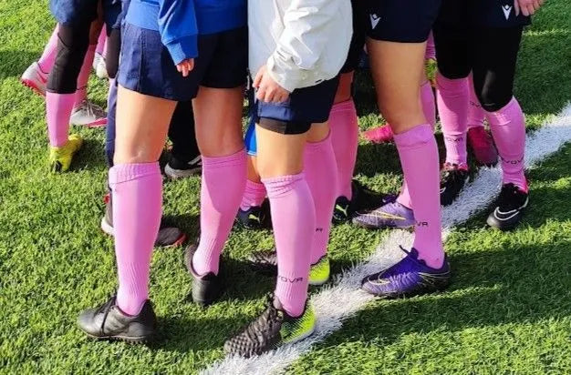 Group of soccer players with pink socks on a grass field
