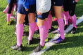 Group of soccer players with pink socks on a grass field